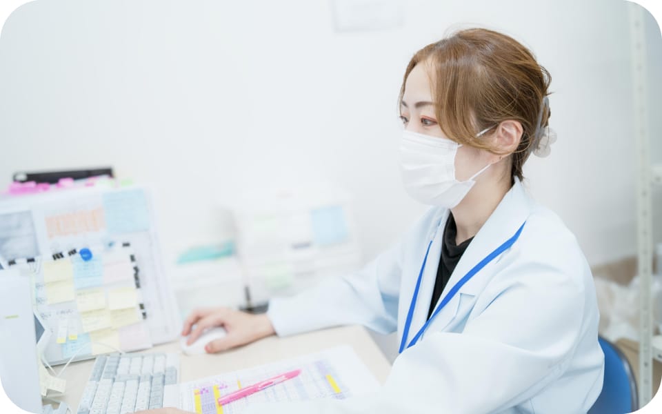 薬局の事務デスクでパソコンに向かい処方せん入力をおこなうスタッフ