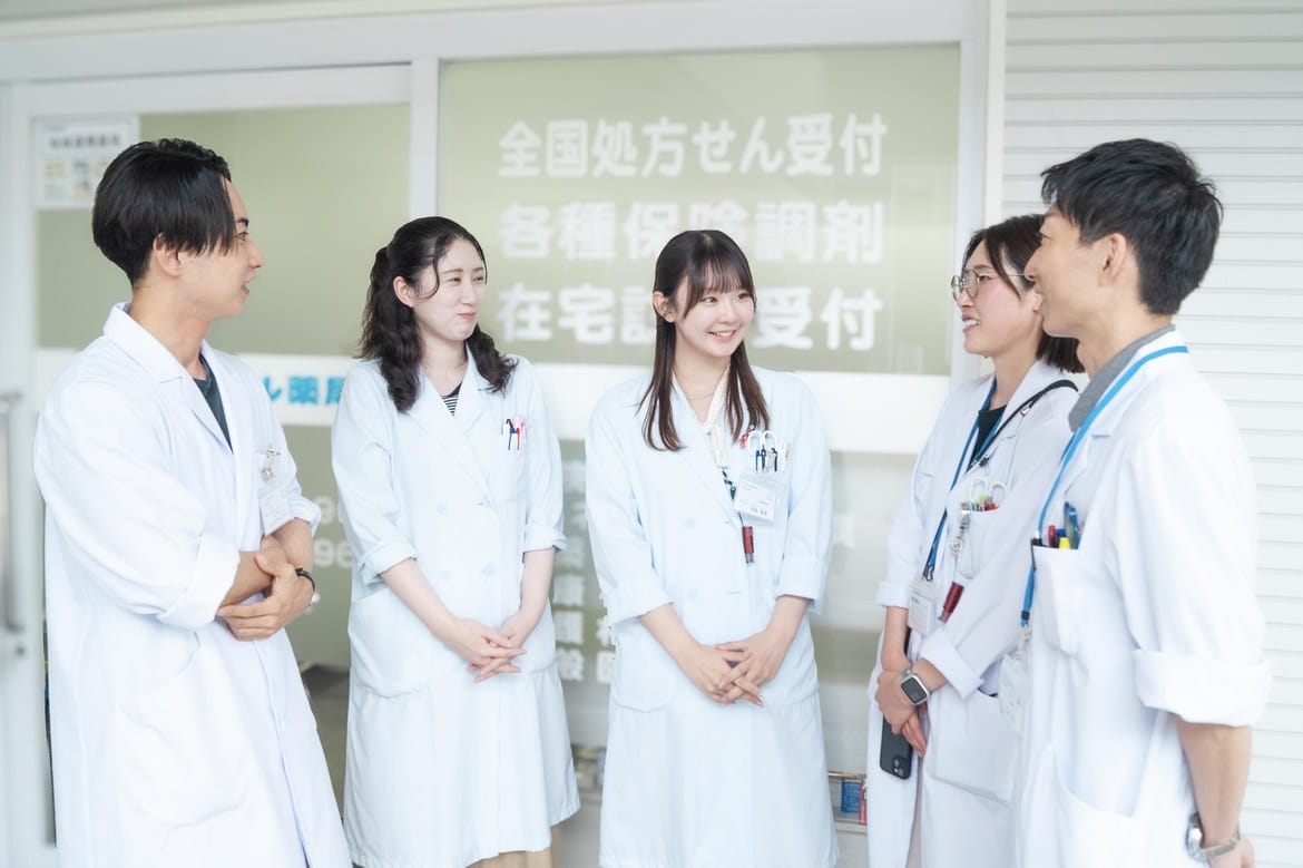 薬局の受付前で笑顔で語り合うセントラル薬局グループの薬剤師とスタッフ